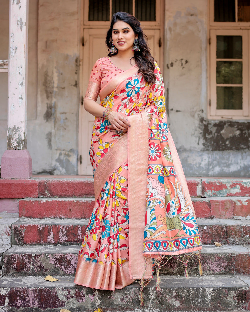 Full shot of woman in peach Tussar silk saree with vibrant floral digital print, standing on steps.
