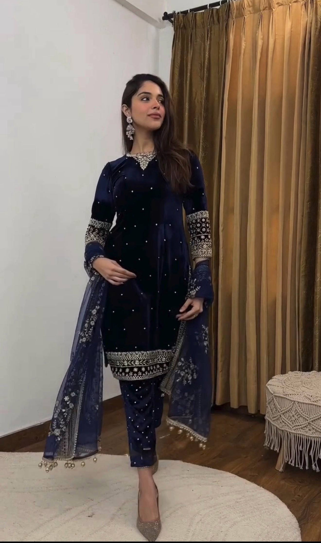 Woman posing, showcasing a navy blue velvet kurta pant set with intricate gold embroidery and a delicate butterfly net dupatta.
