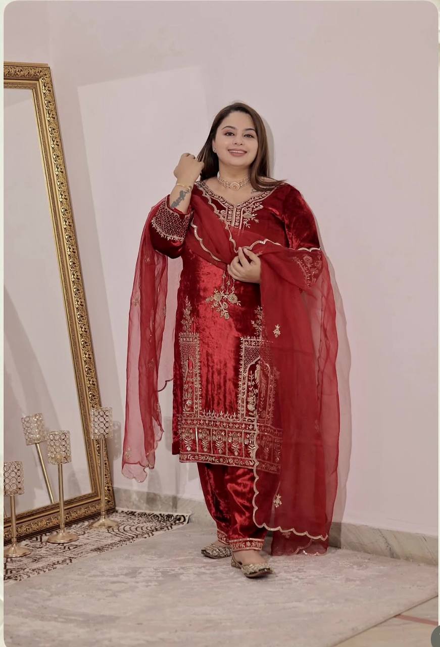Full shot of a woman modeling a maroon velvet embroidered Patiyala suit with a matching dupatta.