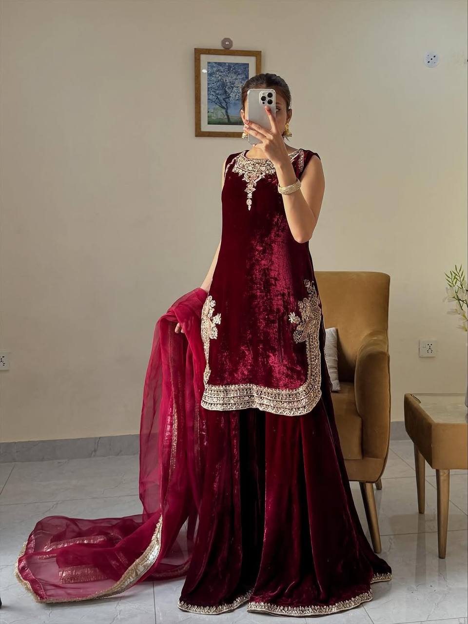 Front view of a woman showcasing a luxurious deep red velvet kurta palazzo set, highlighting the detailed embroidery work and rich fabric.