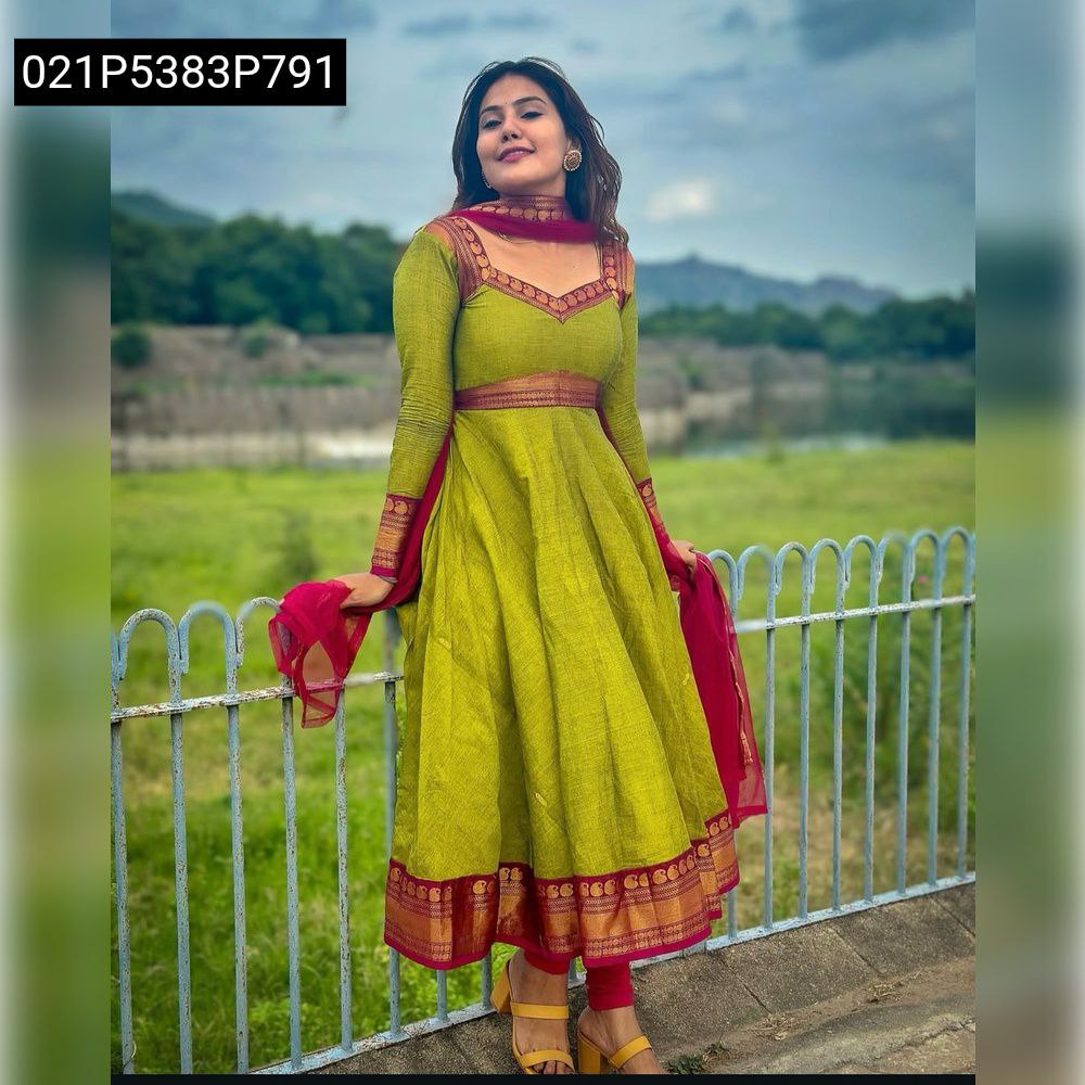Full body shot of a woman in a green Vichitra Silk Anarkali Gown with pink net dupatta, standing outdoors