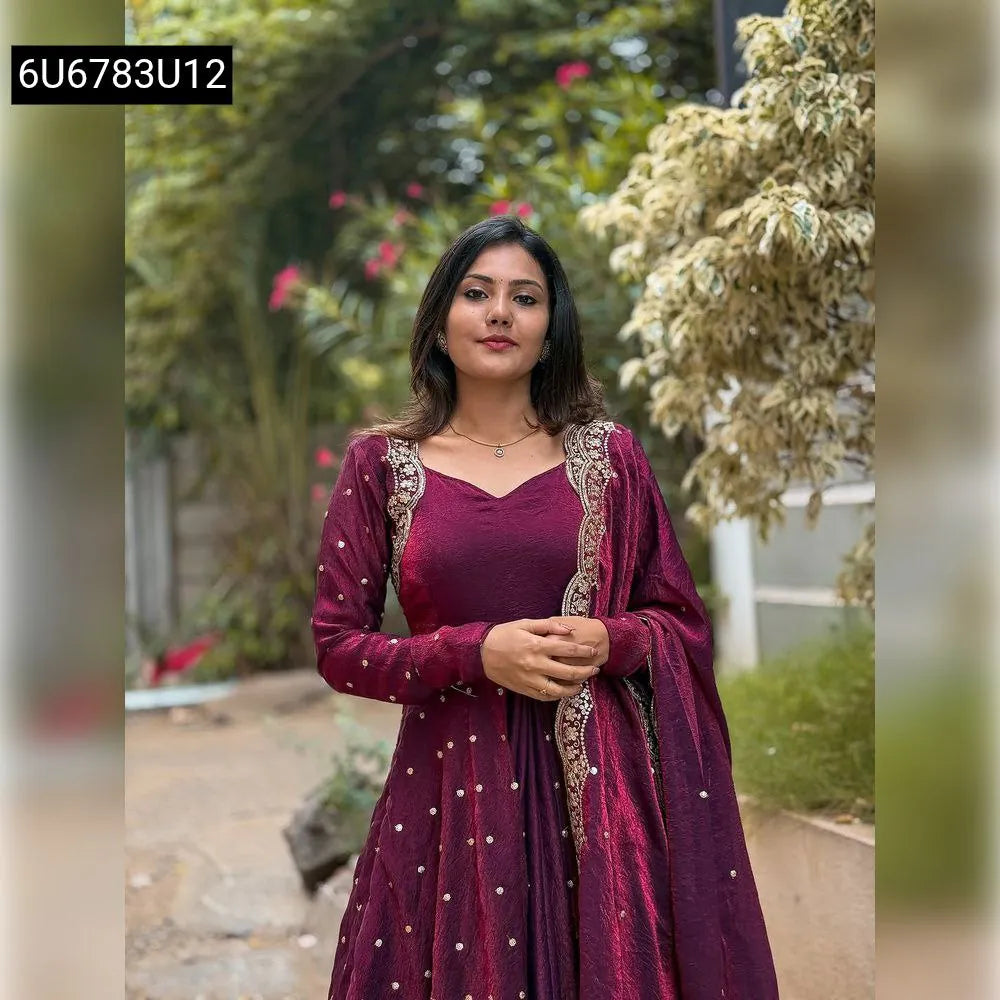 Woman wearing a Wine Vichitra Silk Anarkali Gown with gold embroidery, front view in a garden setting.
