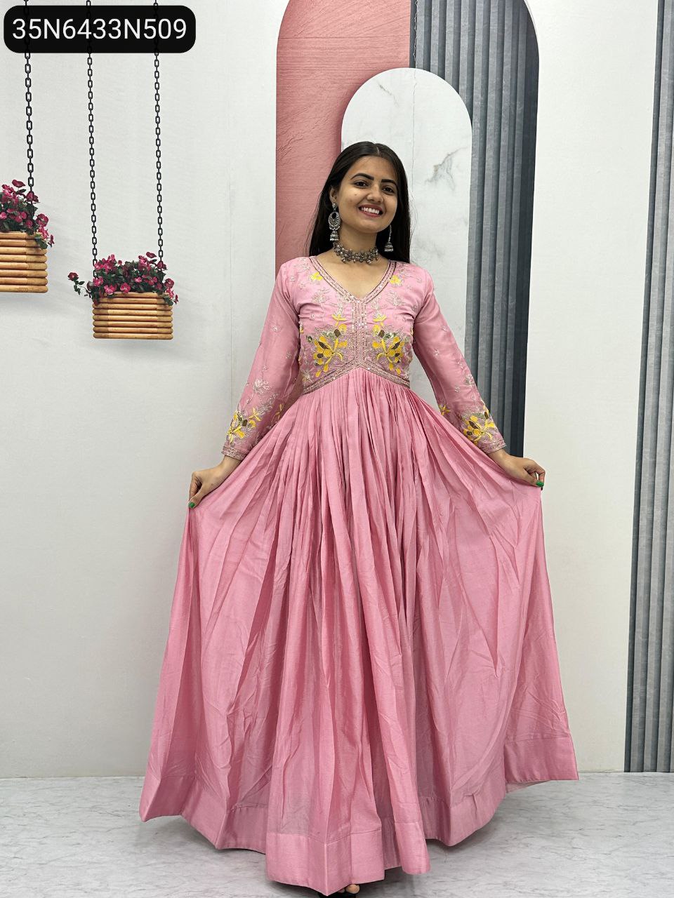 Front view of a smiling model wearing a beautiful pink embroidered Chinon gown for women's party wear.
