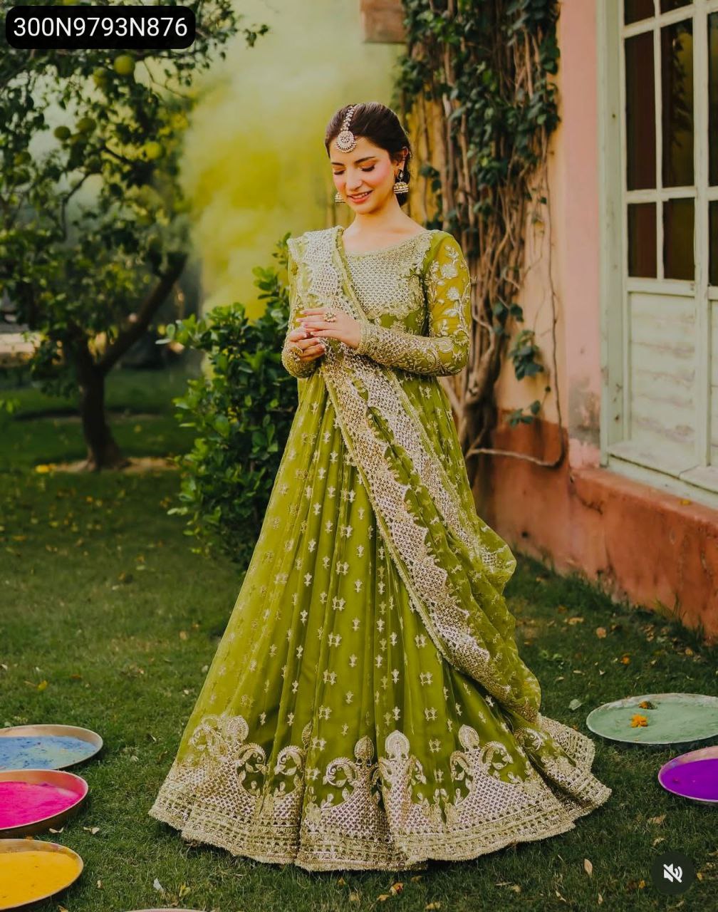 Woman in a green embroidered Fox Georgette gown with dupatta posing elegantly in a garden.