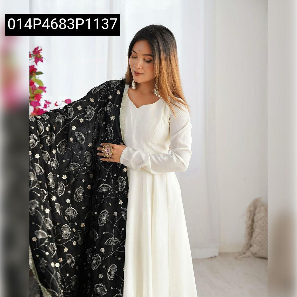 Woman posing in an elegant white Georgette Anarkali gown with a black embroidered dupatta.