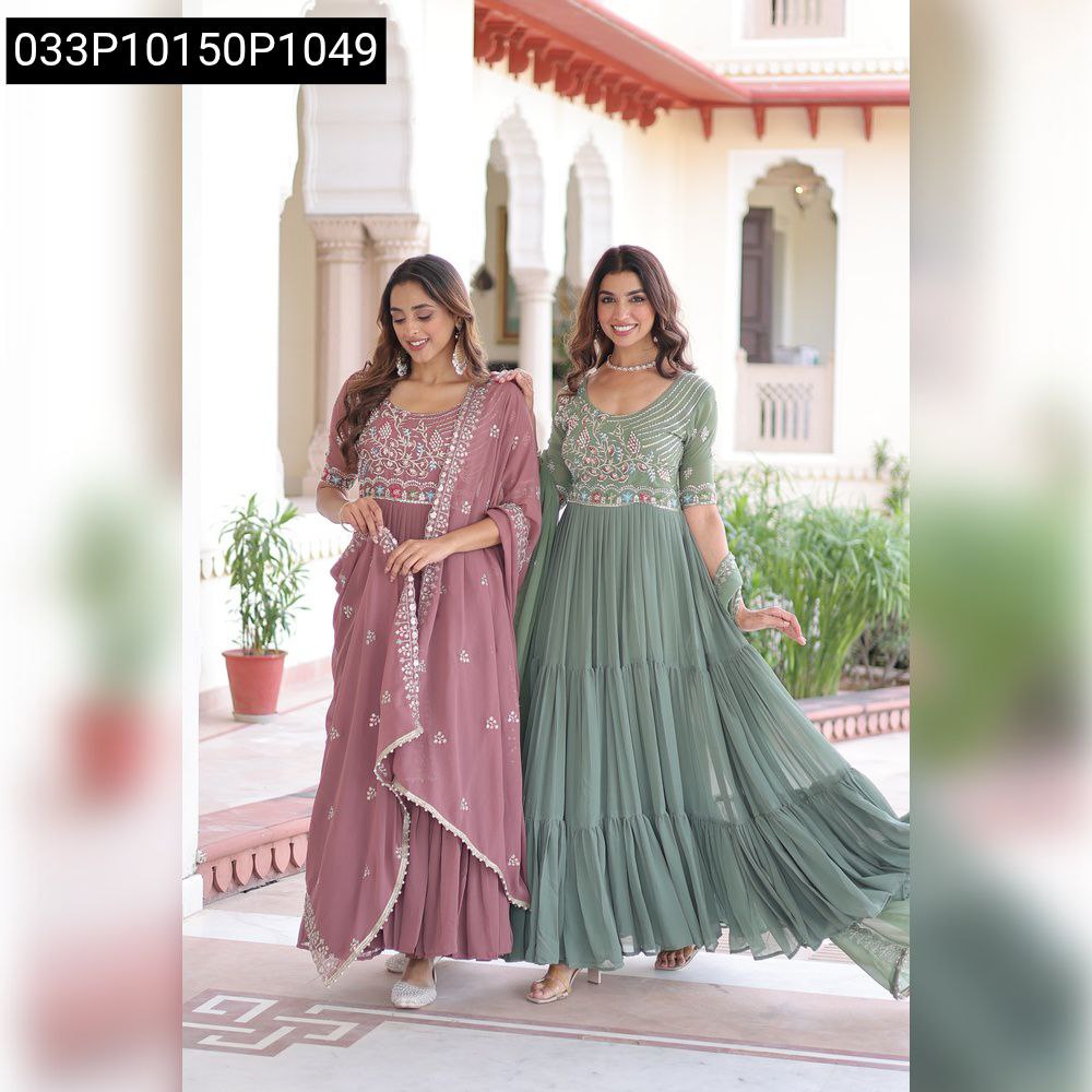 Two women wearing full-length embroidered tiered gowns, one in lavender, one in sage green, posing elegantly in an archway.