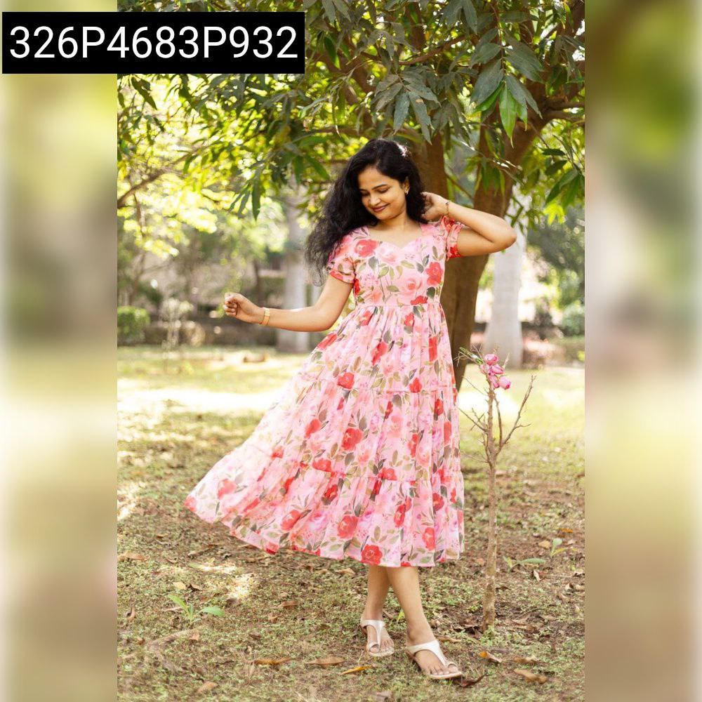 Model wearing a pink floral tiered maxi dress in a serene outdoor setting, exuding graceful charm.