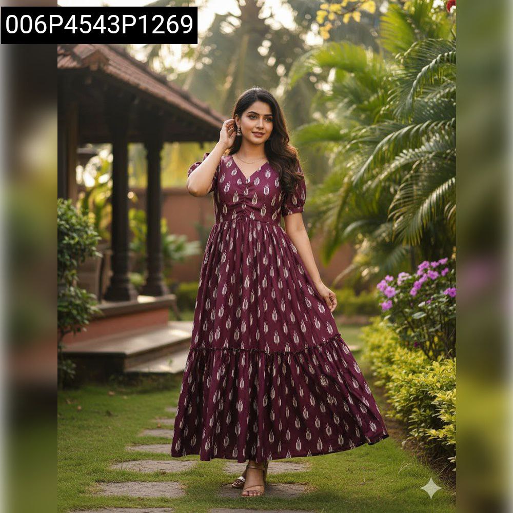 Model in plum ikat tiered dress with short sleeves, posing in a garden setting.