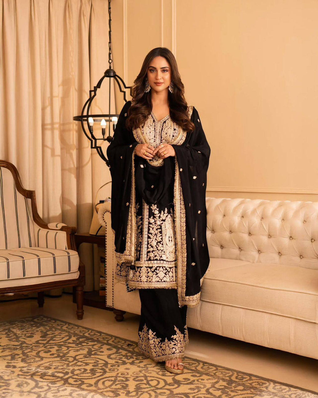 Full body shot of a woman standing gracefully in a black georgette kurta set, highlighting the beautiful gold embroidery on the kurta, pant, and dupatta, suitable for festive occasions.