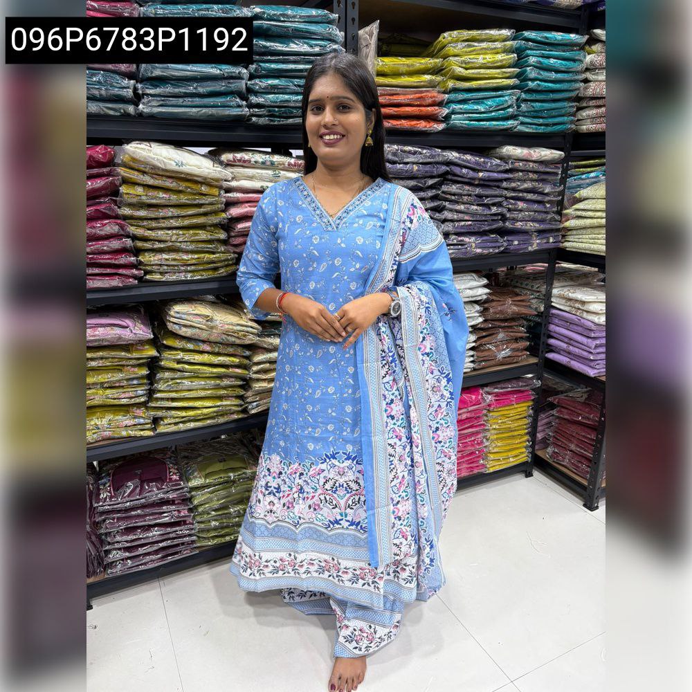 Full body shot of a woman in a light blue kurti set with floral print, smiling.