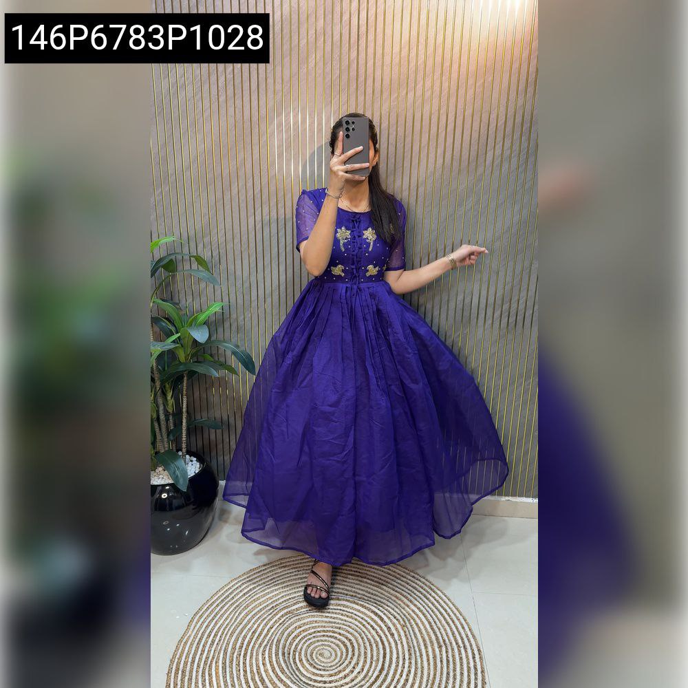 Full body shot of a woman in a purple Kota Check cotton gown with hand work, holding a phone.