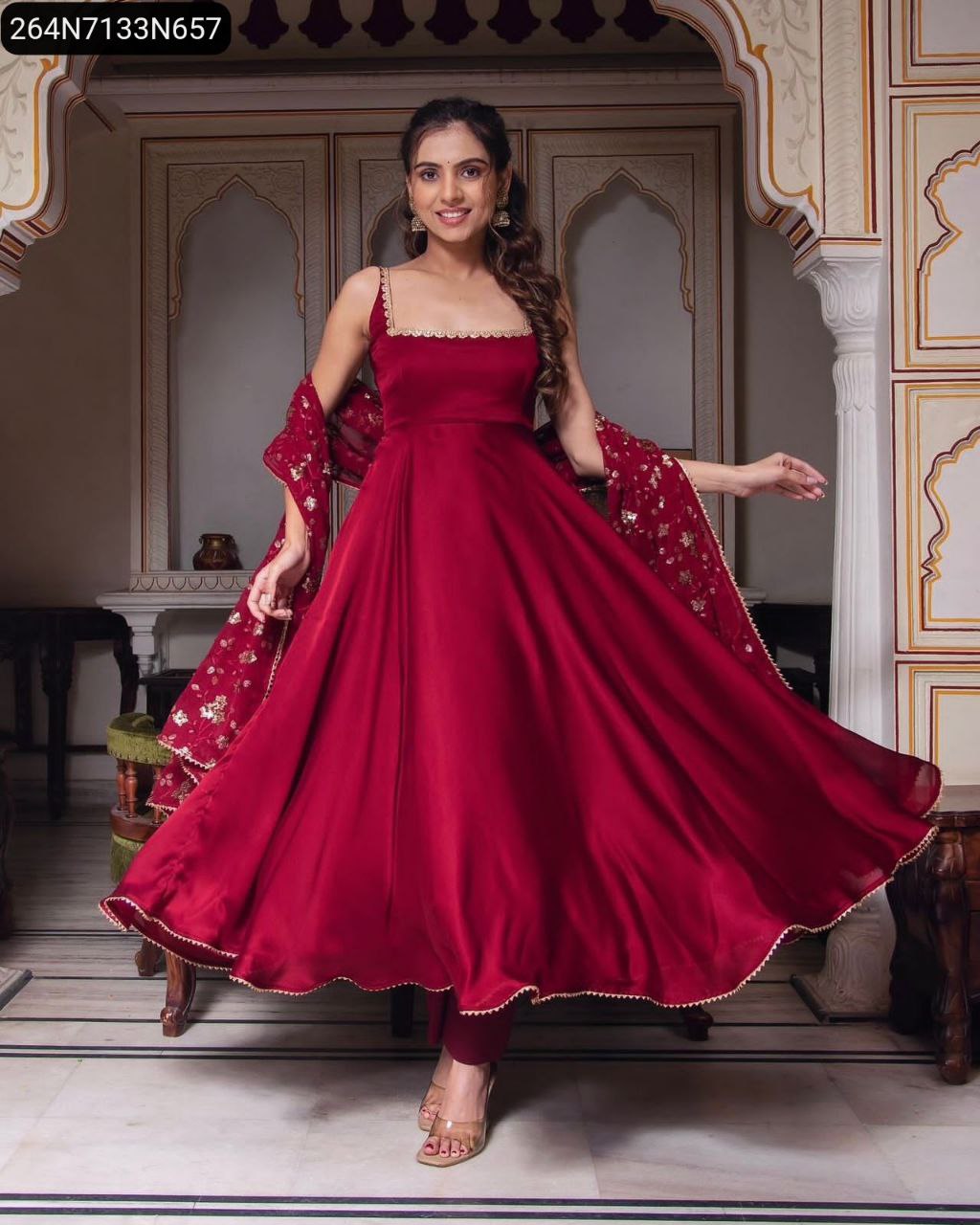 Full body shot of a model twirling in the red designer party wear gown with matching dupatta.