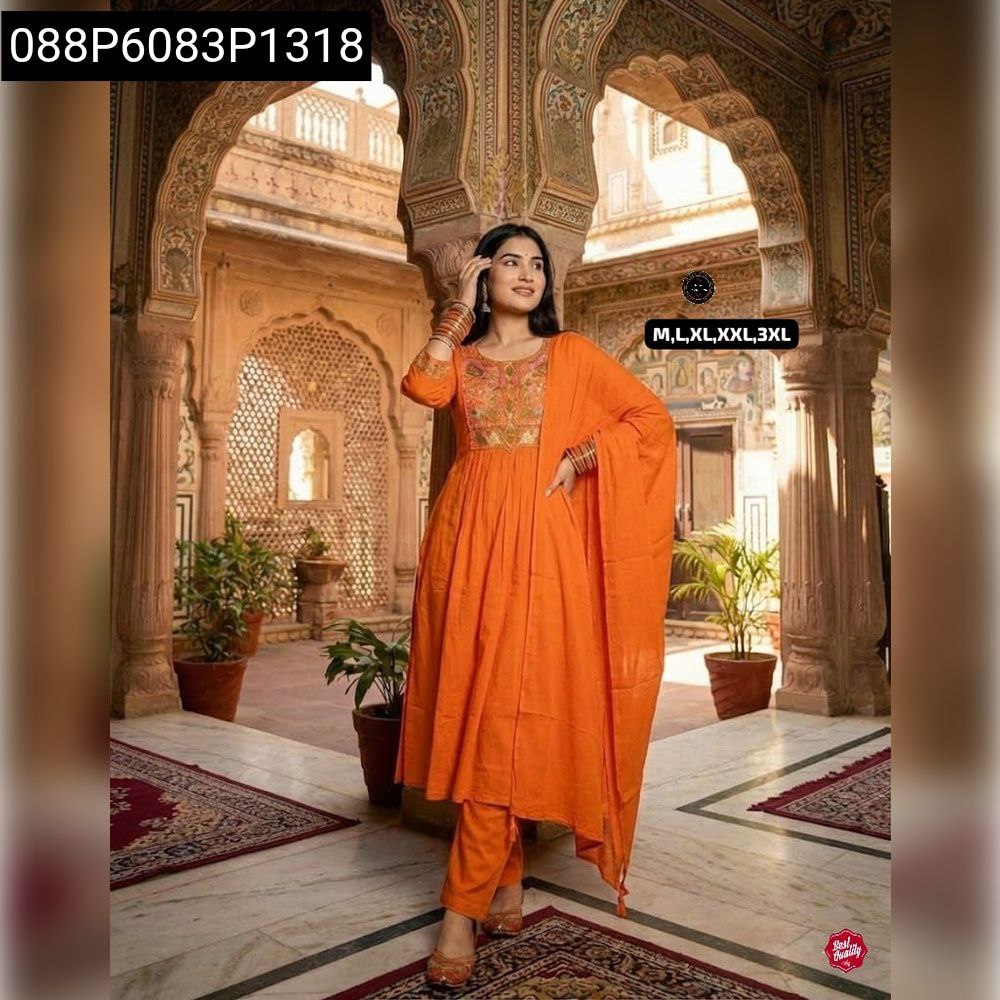 Woman in orange Anarkali kurti set with floral embroidery, posing gracefully in a courtyard