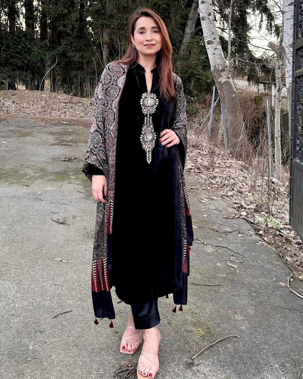 Woman wearing elegant black velvet three-piece suit with intricate sequence embroidery and a patterned Ajrakh dupatta.