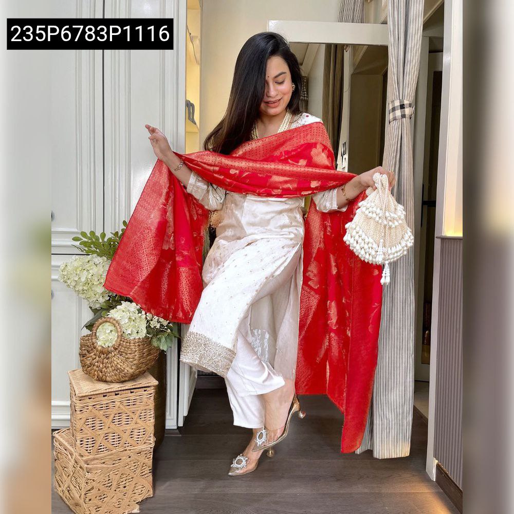 Full shot of a model wearing a white kurti set with a red jacquard dupatta, posing indoors with decorative baskets.